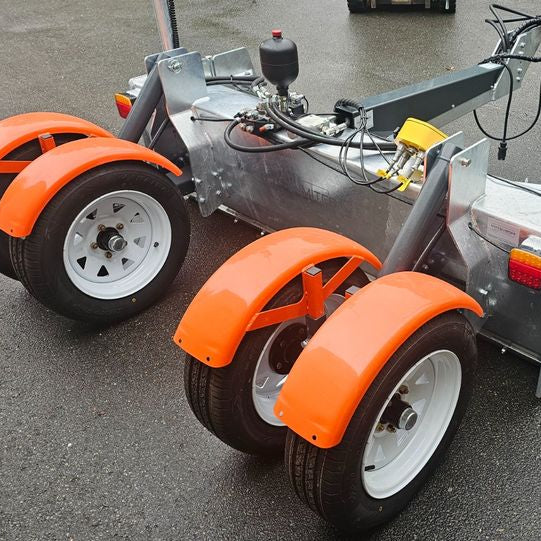 Planierhobel von hinten, vier Räder mit orangefarbenen Kotflügeln